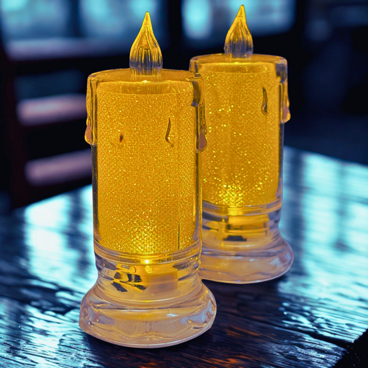 Two gold glittery candles on a reflective surface with a blurred background